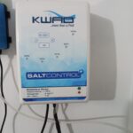 Boîtier de commande d'un électrolyseur au sel fixé au mur d'un local technique de piscine