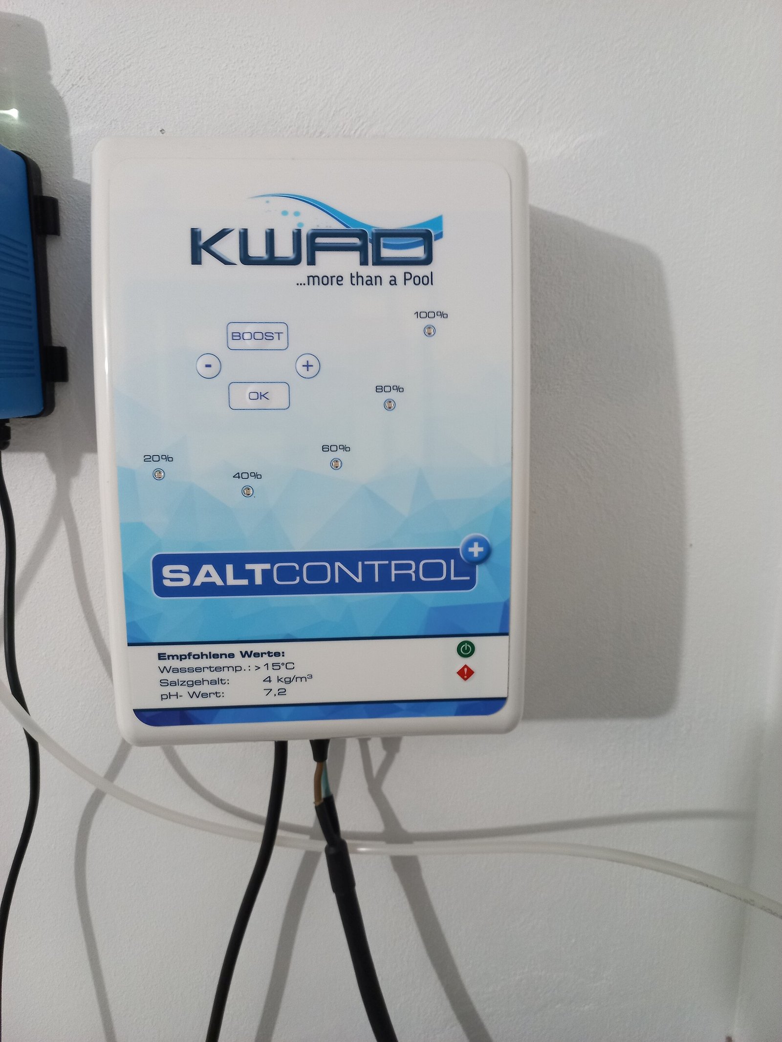 Boîtier de commande d'un électrolyseur au sel fixé au mur d'un local technique de piscine
