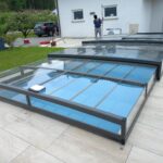 Abri de piscine télescopique recouvrant un bassin dans un jardin