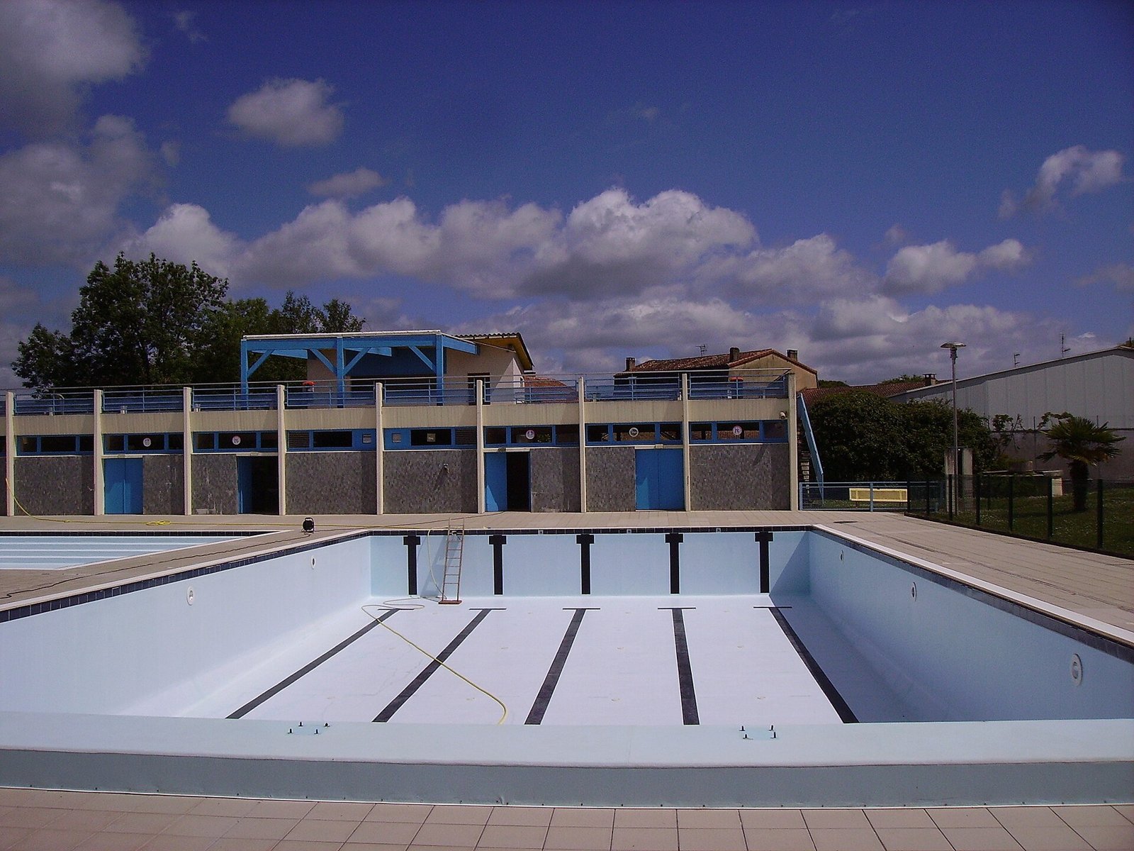 Bassin de piscine extérieure entièrement vidé, au revêtement blanc et aux lignes bleues
