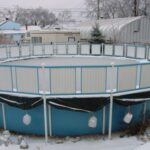 Piscine hors-sol hivernée dans un jardin enneigé