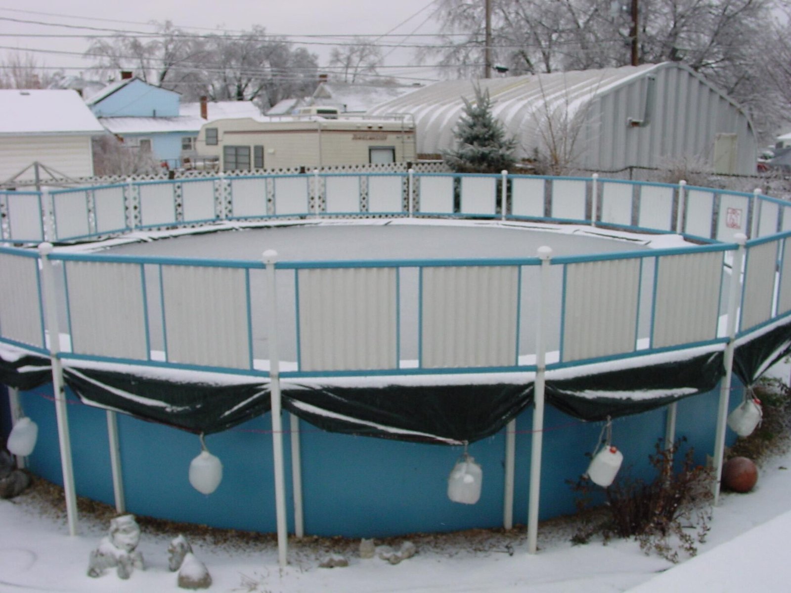 Piscine hors-sol hivernée dans un jardin enneigé