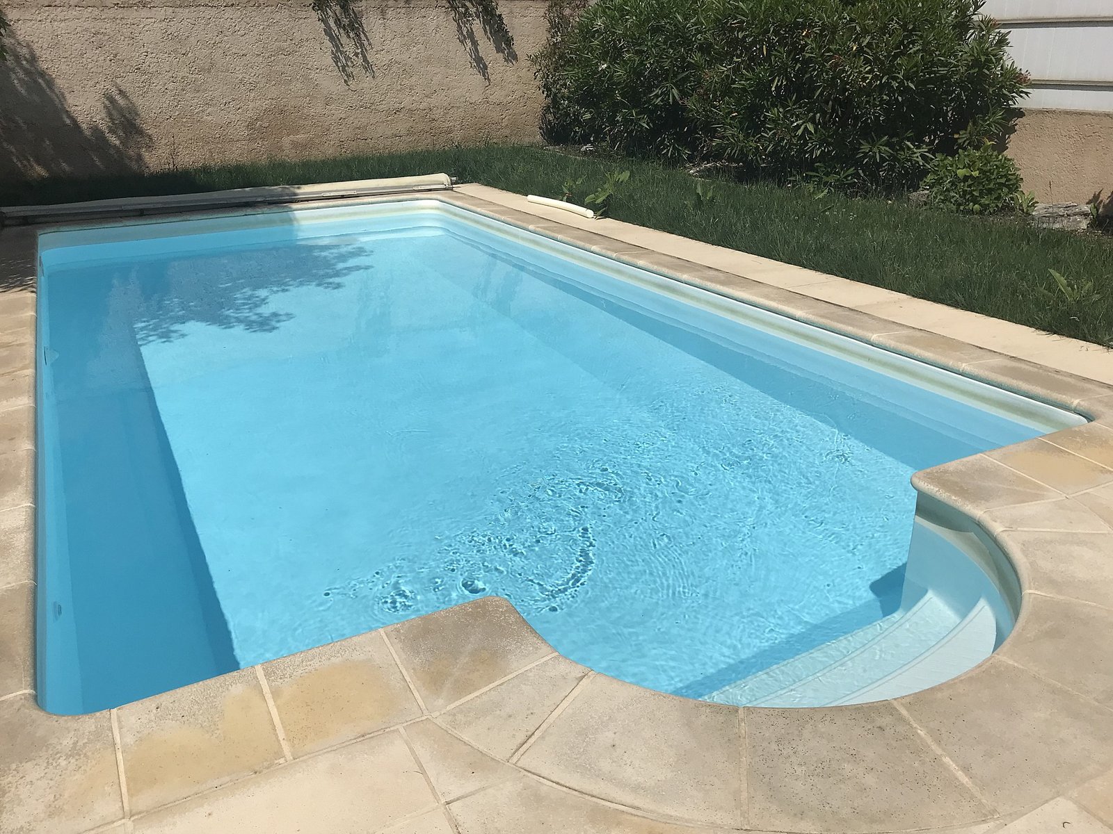 Piscine privée enterrée dans un jardin, avec volet roulant